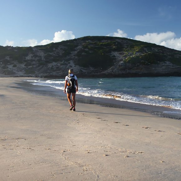 Hiker walking along the beach below the Robberg cliffs